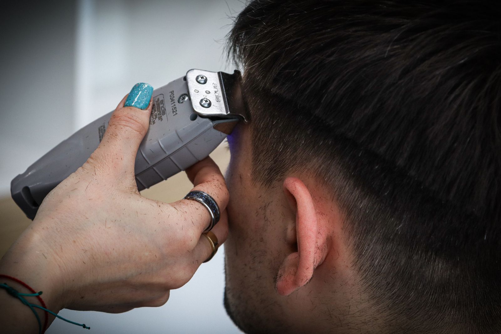 Close-up of a barber using electric clippers to cut a fade