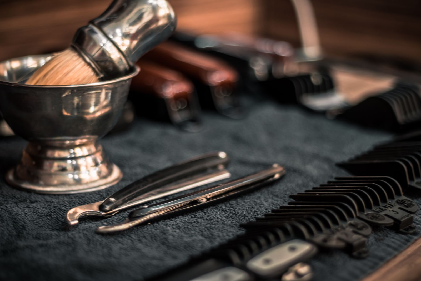 Barber tools including straight razors, clippers and combs arranged on a surface