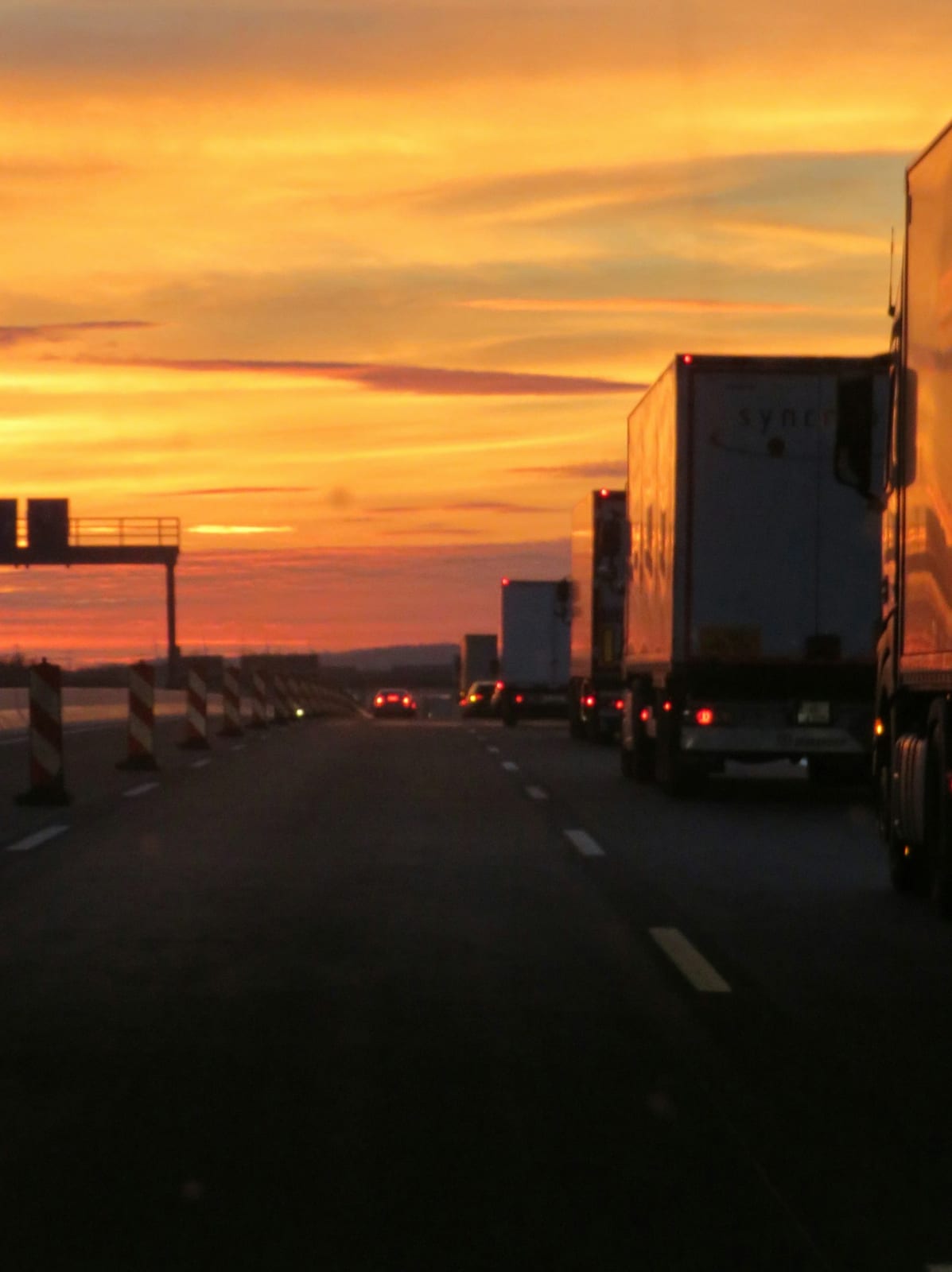 A semi-truck driving down a highway at sunset