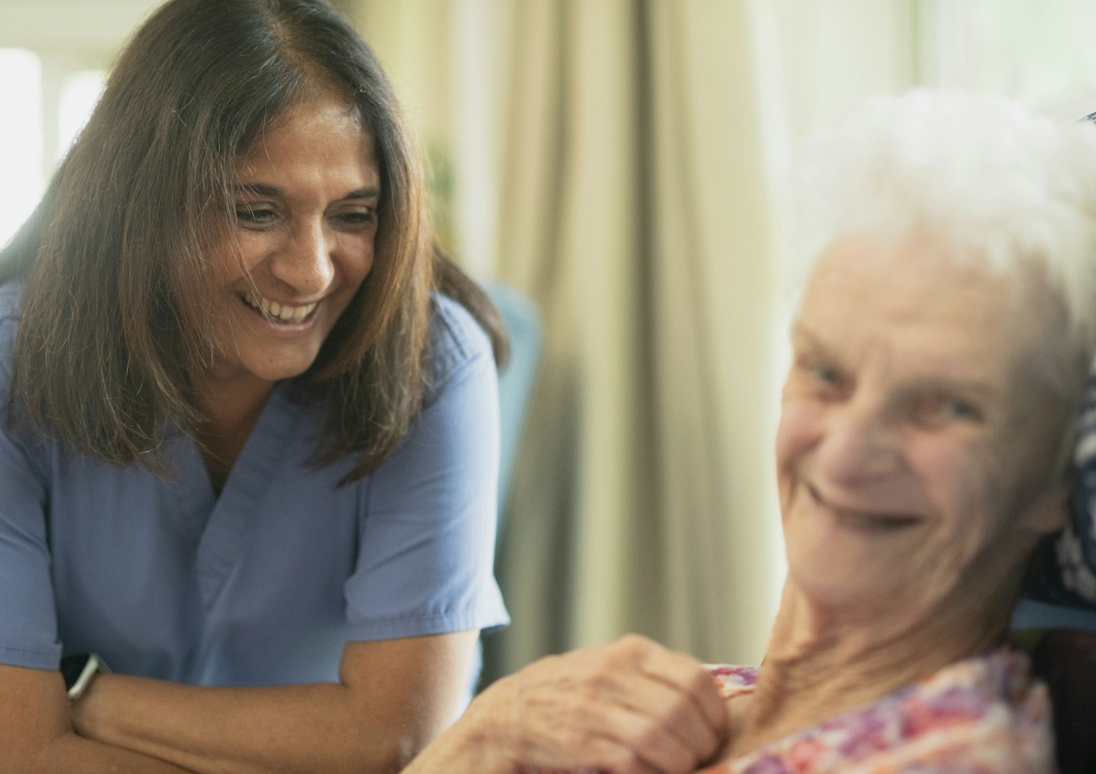A nurse smiling with an elderly patient in a care setting