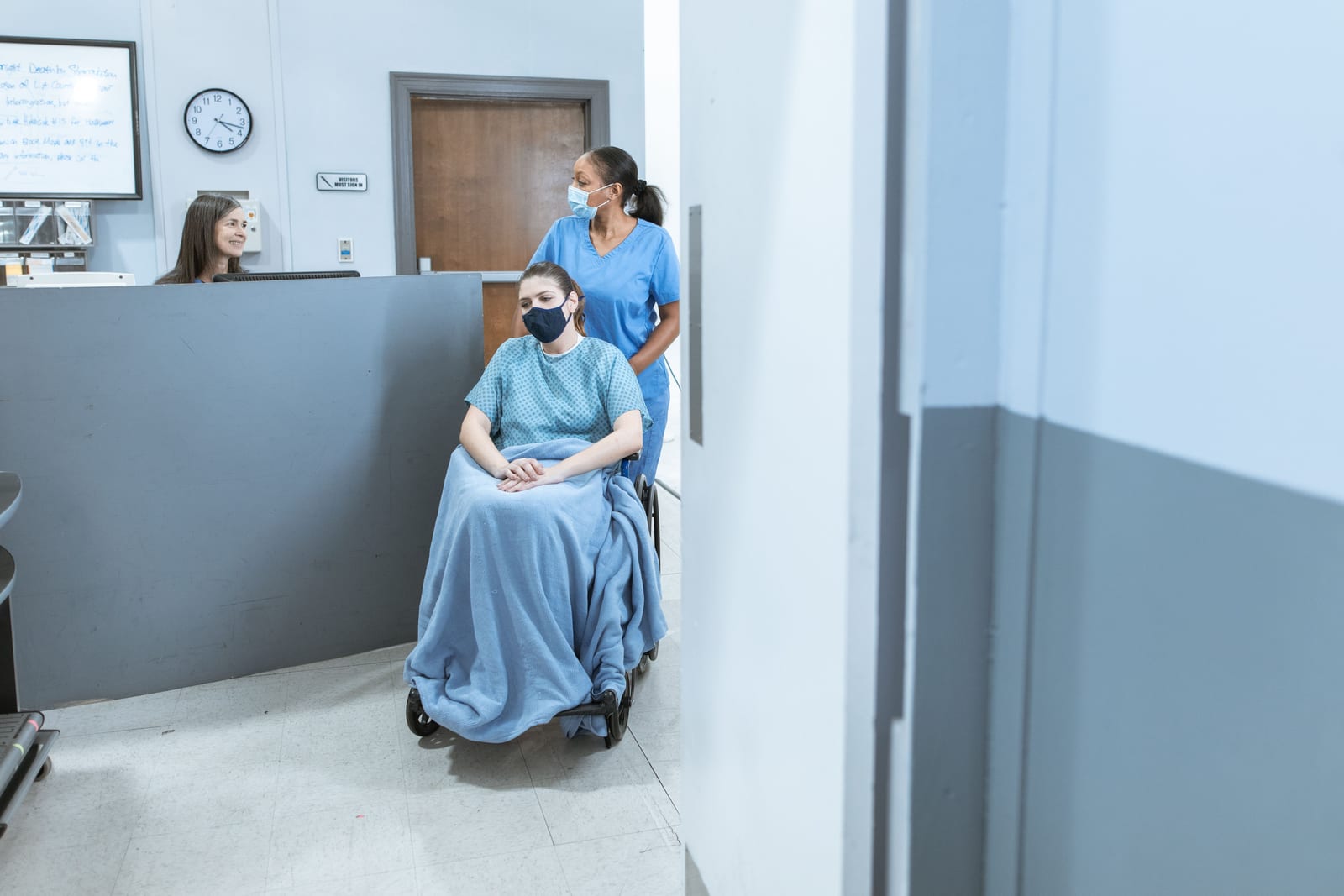 A healthcare worker assisting a patient seated in a wheelchair at a medical facility