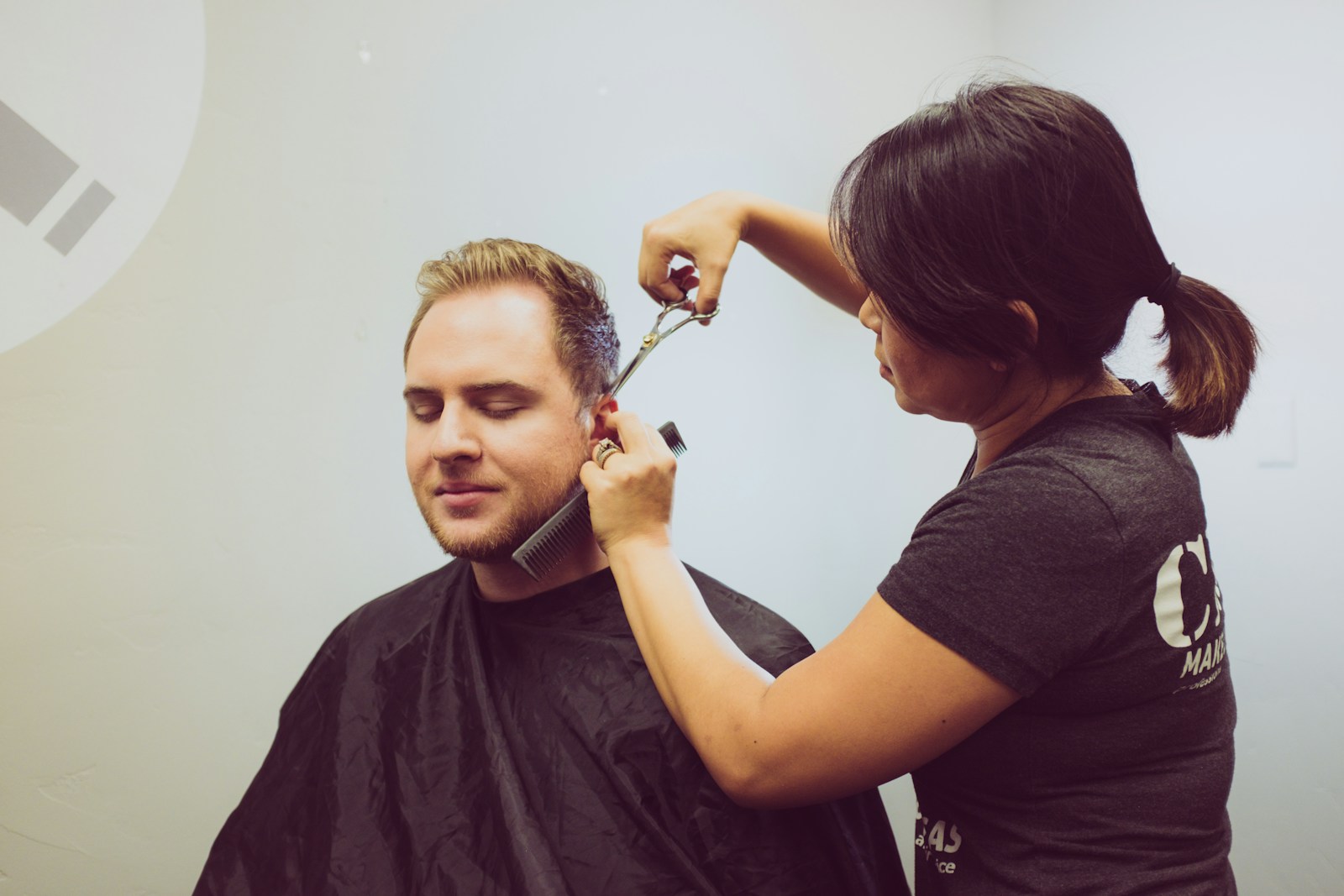A stylist cutting a client's hair chair-side in a salon