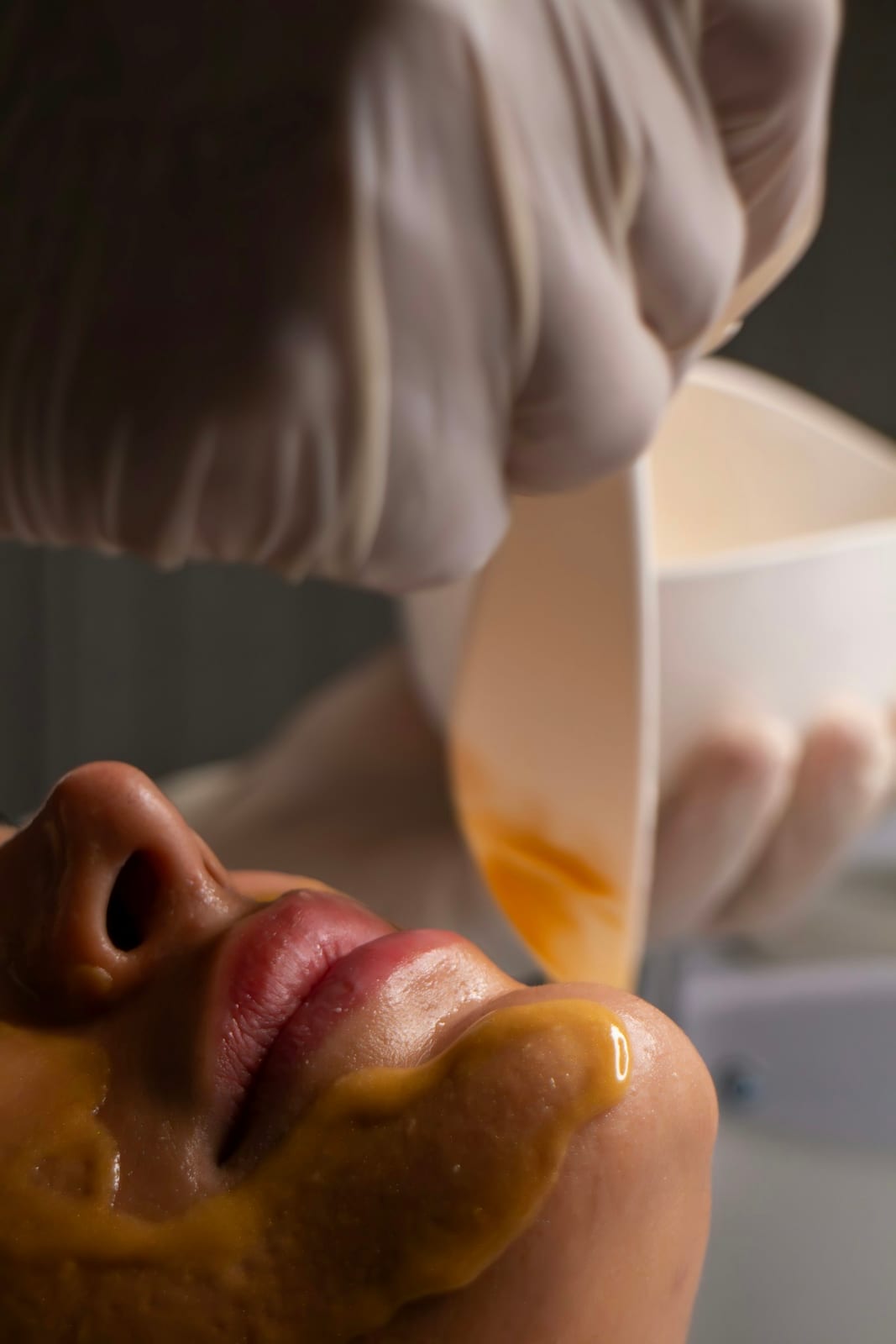 A beauty professional applying a facial mask to a client during a treatment