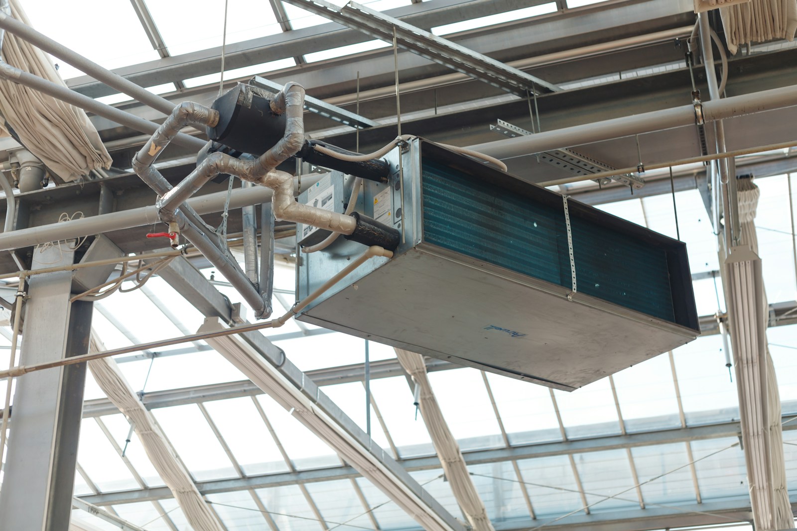 A ceiling-mounted air handler unit with ductwork and insulation in a commercial building