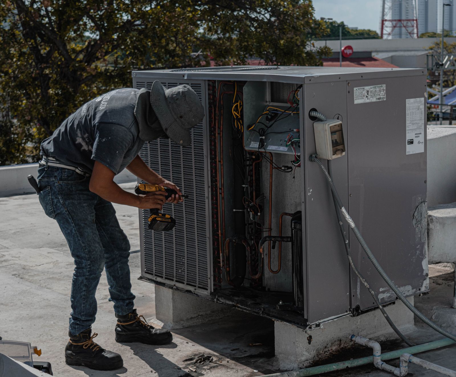 A technician servicing a rooftop air conditioning unit