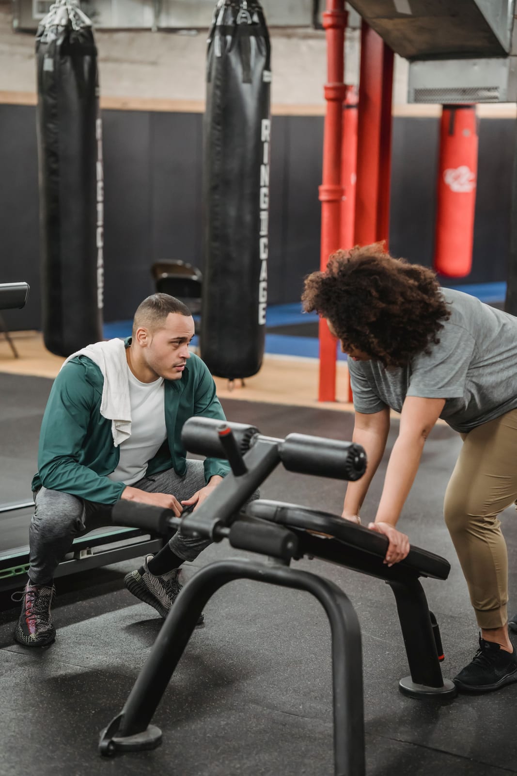 A personal trainer guiding a client through an exercise on gym equipment