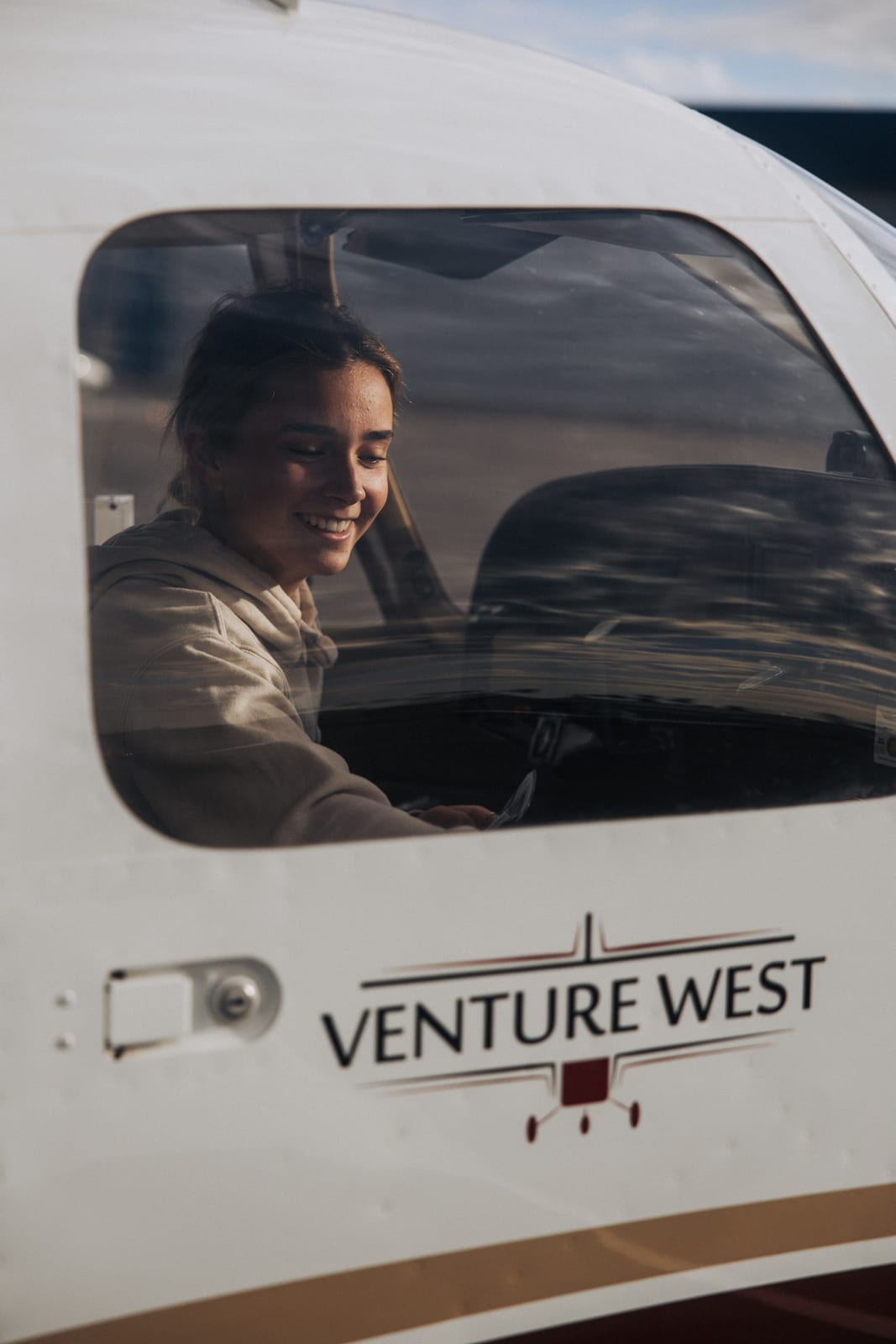 A student pilot smiling in the cockpit of a training aircraft