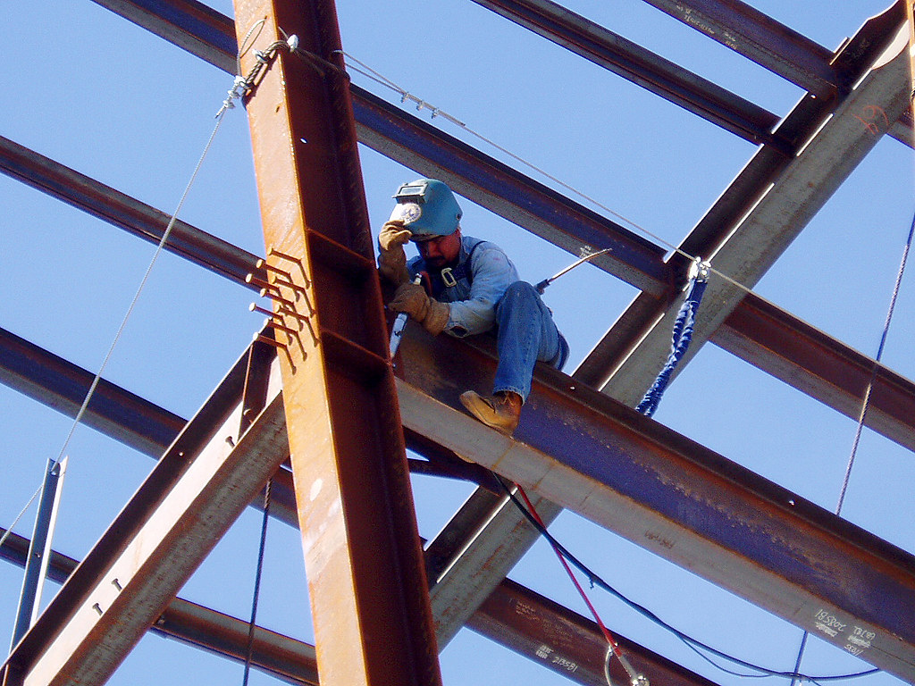 A welder working on structural steel high above a construction site