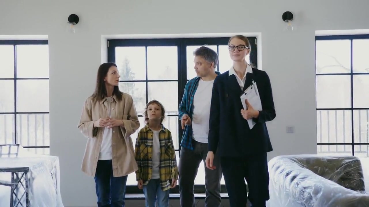 A real-estate agent with a clipboard walking a family through an empty house.